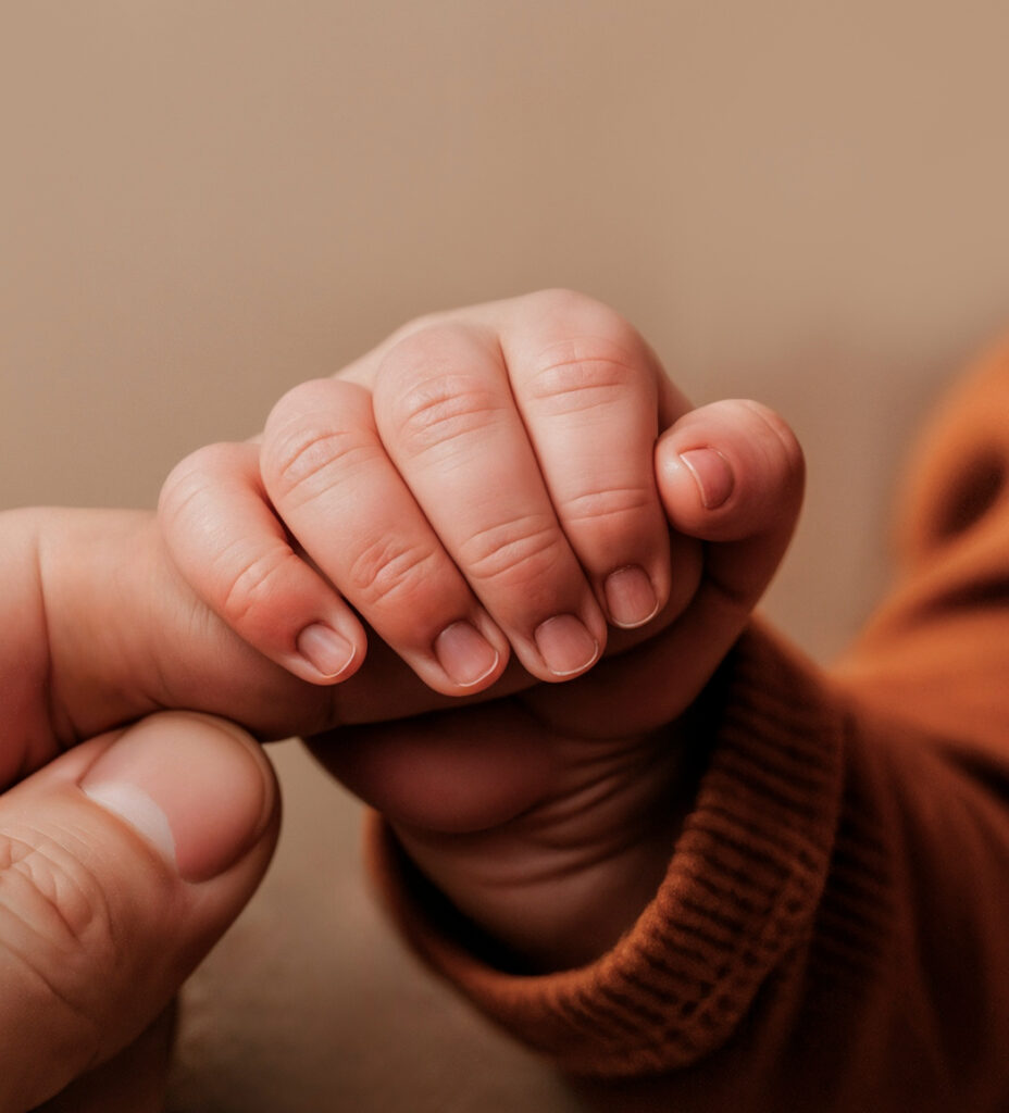 Baby boy holding an elder's finger
